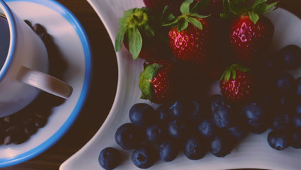  A cup of coffee and coffee beans, blueberries and strawberries