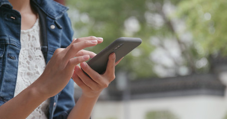 Close up of woman sending sms on cellphone in Chinese garden