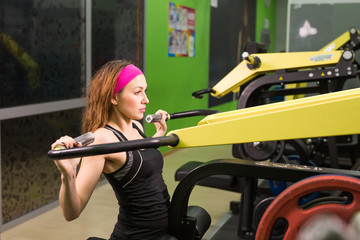 Fototapeta na wymiar Beautiful woman at the gym exercising on a machine.