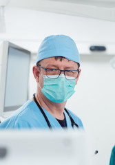 Anesthetist watching patient sleeping in operation room monitoring vital functions