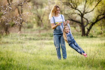 young mother with adorable daughter in park with blossom tree