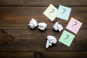 FAQ concept. Question mark on sticky notes near crumpled paper on dark wooden background top view copy space