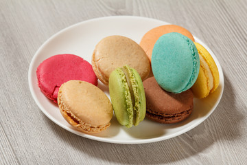Delicious macarons cakes of different color on white porcelain plate