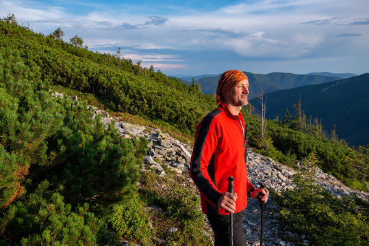 Happy hiker stands on a mountain trail