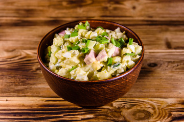 Ceramic bowl with russian traditional salad olivier on wooden table