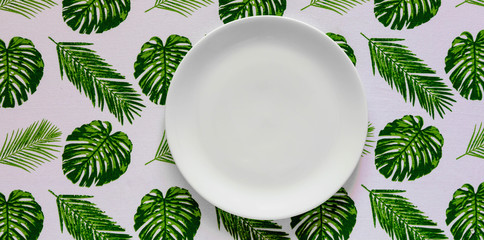 Top view of clean white plate on Palm leaves tablecloth