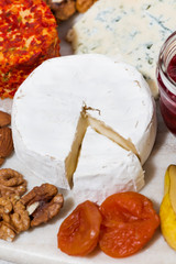 assortment of snacks with cheeses, fruits and nuts, vertical closeup