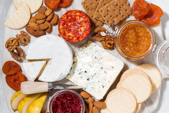 assortment of gourmet cheeses and snacks on board, top view