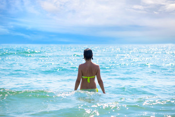 Fototapeta premium Back view of a pretty young woman on the sea