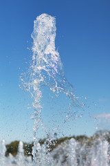 Splash water fountain on blue sky in a park