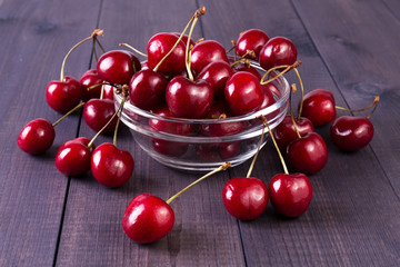 Obraz na płótnie Canvas Red cherries in a bowl. Sweet berries on wooden background. Angle view