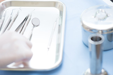 Metallic dentist tools close on and blue table sheet in a dentist clinic. with dentist hand 