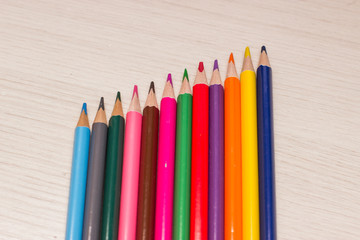 Pencils of different colors are on the table made of wood gray