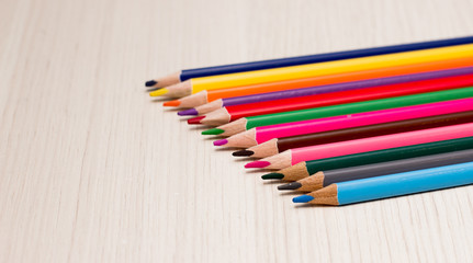 Pencils of different colors are on the table made of wood gray