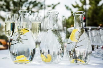 Fresh homemade lemonade with sprig of rosemary in a glass bottle on a table