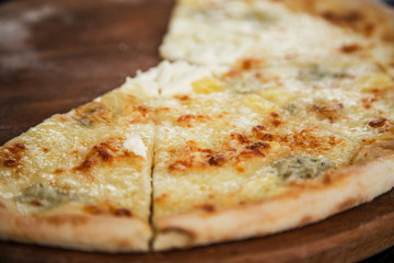 Pizza quattro cheeses on a rustic wooden board background