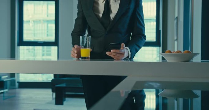 Businessman using smartphone and drinking juice in slow motion