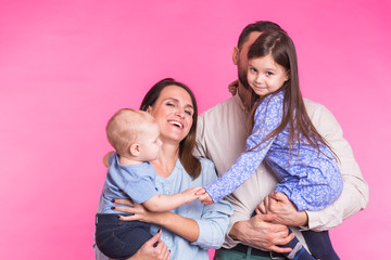 Cute family posing and smiling at camera together on pink background