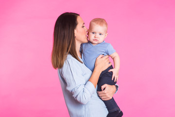 happy young mother with a baby child on pink background