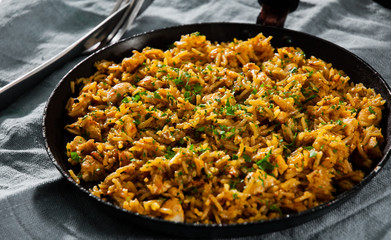 Chicken Breast with Rice and vegetables in a frying pan on dark wooden background