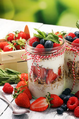 Glass jar of homemade granola with yogurt and fresh berries