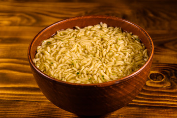 Ceramic bowl with prepared instant noodles on wooden table