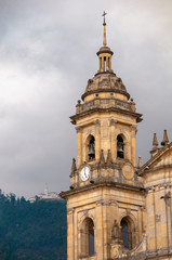 Fototapeta na wymiar Bell tower with clock of the cathedral in the Plaza Simón Bolívar with church of Monserrate in the mountain in the background.Bogota. Colombia .