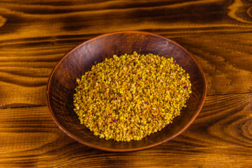 Ceramic plate with bee pollen on wooden table