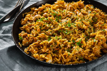 Chicken Breast with Rice and vegetables in a frying pan on dark wooden background