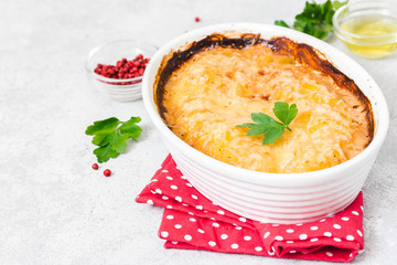 Golden crust potato gratin in baking dish on concrete background. Selective focus, space for text.