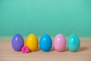 row multi colored painted Easter eggs and flower over green background, copy space