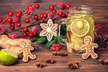 mason jar with New year ice tea with ginger, lime, cinnamon and gingerbread, decorated Christmas tree branch, cones and anis, greeting card, toned style