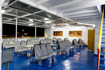 empty lounge on the night voyage of the ferry, porthole and blue illumination at night