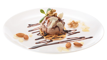 Chocolate ice cream ball decorated with chocolate syrup, mint leaves and almond slices on a white plate