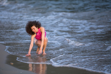 Young beautiful mixed race woman on the surf line at sea beach.