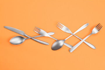 Cutlery on orange background flat lay
