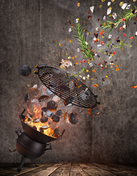Kettle grill with hot briquettes, cost iron grid and spices flying in the air.