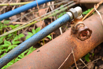 Simple photo background composition image of rusty pipe with valve and plastic hose