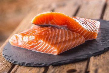 Raw Salmon fillets on slate and wooden board
