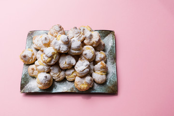 Homemade profiteroles served on a plate. on a pink background