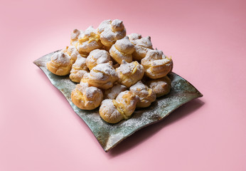 eclairs served on a plate on a pink background. homemade profiteroles