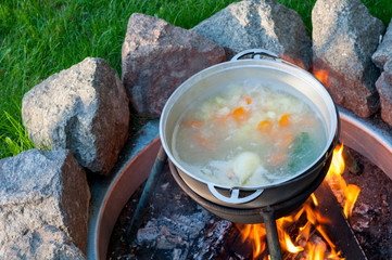 A cauldron with soup, which is cooked on a fire