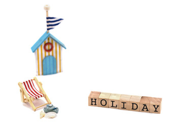 Strandstuhl mit Sandalen, Muscheln, Badehaus, Holzblöcke mit Text Urlaub in Englisch