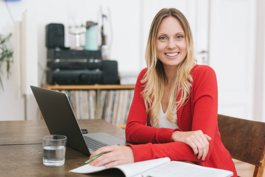 Smiling blonde woman sitting in front ot laptop