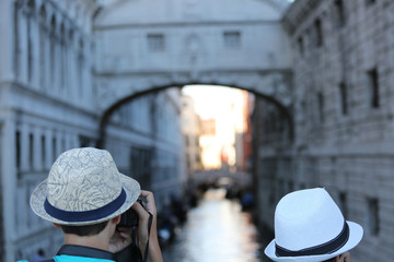 two young tourist with hat and the bridge of sighs in Venice