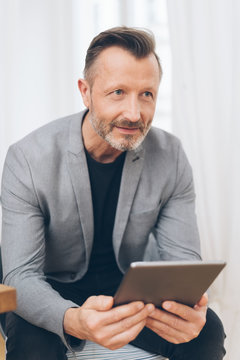 Mature man in grey jacket using digital tablet