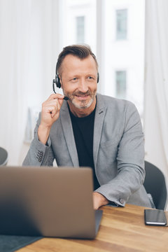 Smiling mature man with headset working at office