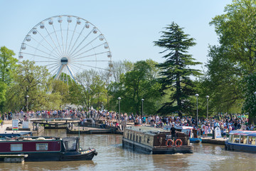 Major crowd gathering around ferris wheel and canal boats for river festival in England 