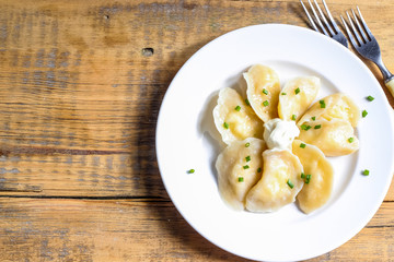 Russian, Ukrainian or Polish dish: varenyky, vareniki, pierogi, pyrohy. Dumplings, filled with cottage cheese and served with sour cream. Top view