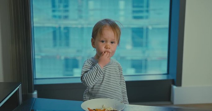 Cute little boy eating lunch in city apartment